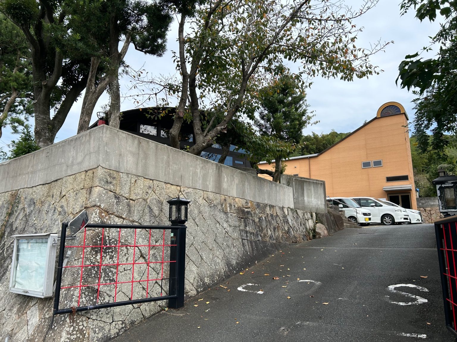 施設の外観。黄褐色の建物と駐車場、緑に囲まれた敷地を示す